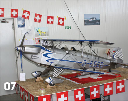 Model biplane on display with Swiss flags and aviation posters.