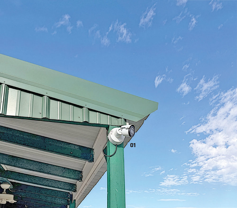 Surveillance camera on a green roof under a blue sky.