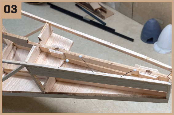Model airplane frame with pins, number 03 in the corner.