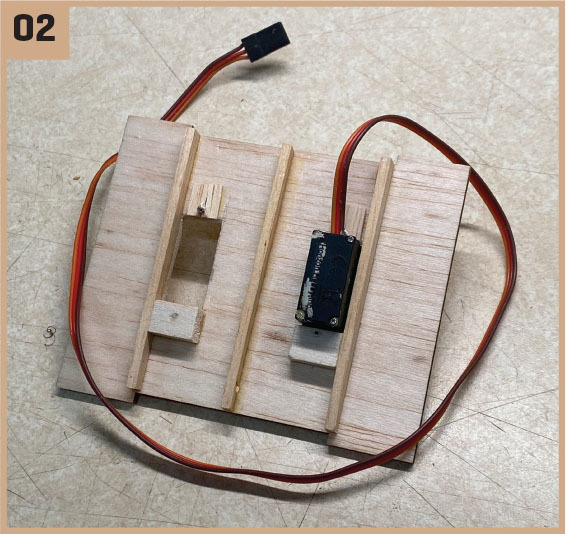 Wooden board with servo motor and cable on a beige surface.