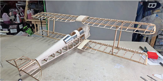 Model biplane with wooden framework on a workbench.