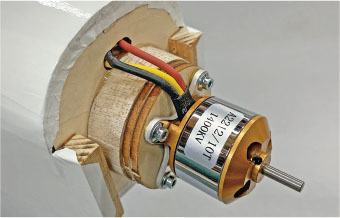 Electrical motor attached to a wooden mount, showing wires and labels.