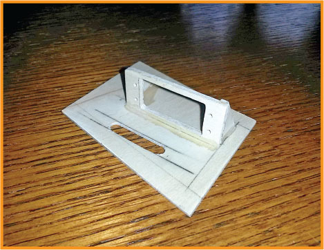 Cardboard model resembling a projector on a wooden surface.