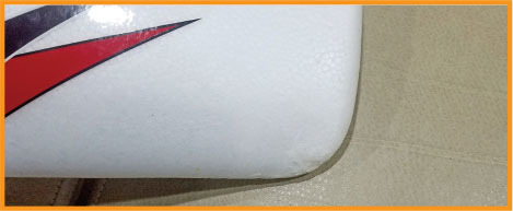 White object with red and black detail on beige surface.