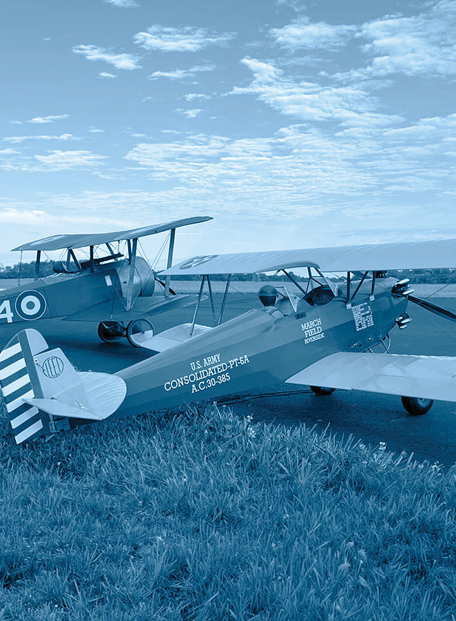 Two vintage biplanes with text "U.S. Army Consolidated PT-6A" and "March Field" on the fuselage.