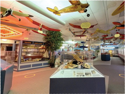 Museum with model airplanes hanging from the ceiling and display cases below.