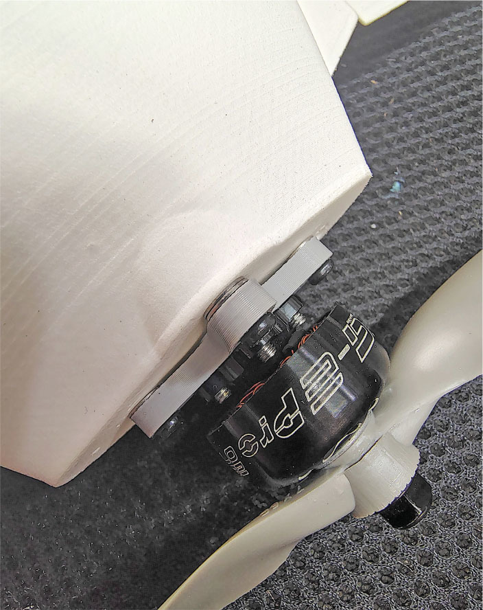 Drone motor on a gray surface, showing wiring and branding.