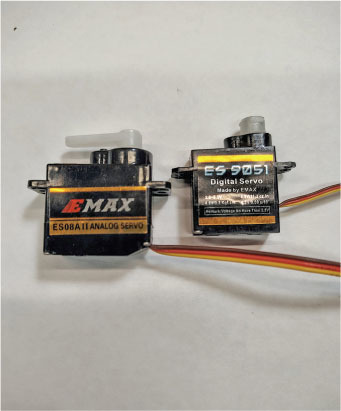 Two EMAX servo motors, ES08AII Analog and ES-9051 Digital, on a light surface.