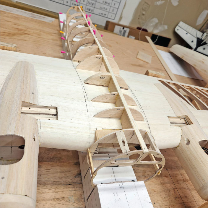 Wooden model airplane under construction on a workbench.