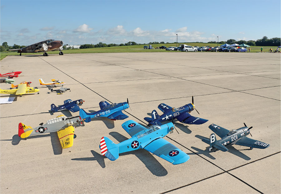 Model airplanes on an airfield, vintage aircraft in the background.