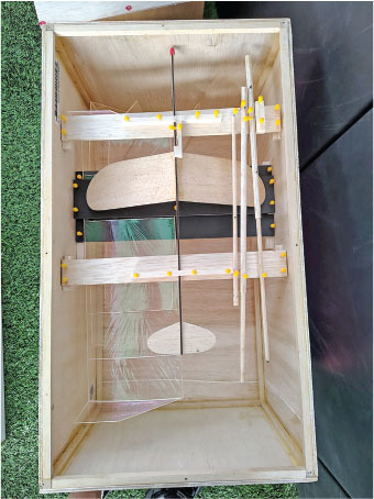 Wooden box with a model glider inside, viewed from above.