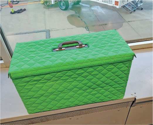 Green quilted case with a handle on a windowsill.