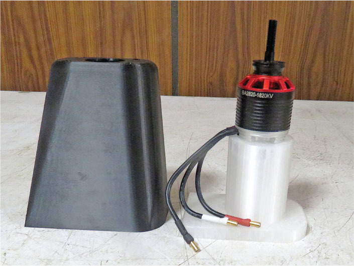 Black cone and labeled motor with wires on white surface.