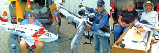 Three men display model airplanes outdoors.