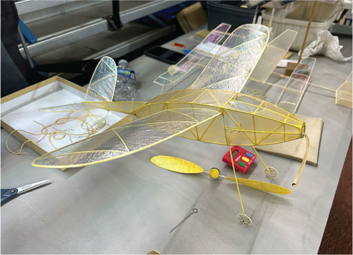 Model airplane with yellow frame and transparent wings on a table.