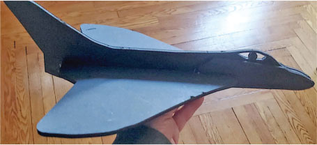 Gray model jet held in hand over wooden floor.