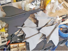Model jet aircraft parts scattered on a workshop table.