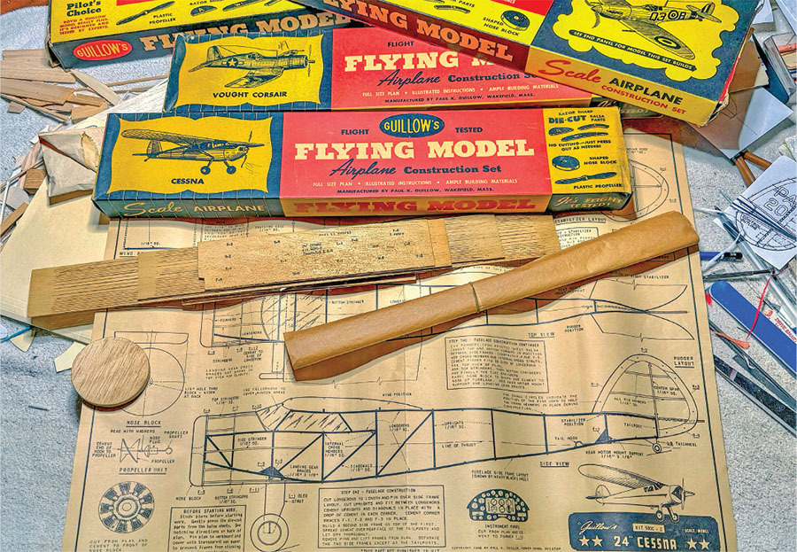Model airplane construction set with plans, wooden parts, and colorful kits.