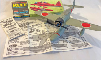 Model airplane kit with instructions and a completed WWII Japanese aircraft.