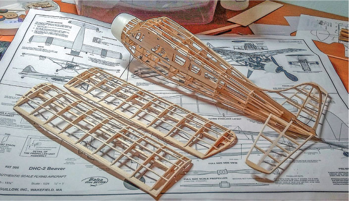 Model airplane skeleton on blueprint with wooden frame parts.