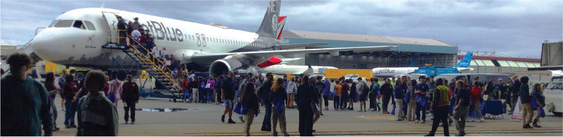 Passengers boarding and exiting an Airbus plane on an overcast day.