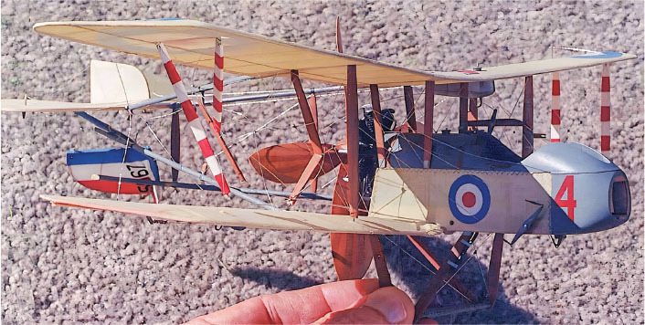 Hand holding a detailed model biplane with red and white markings.
