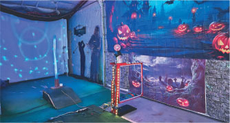 Haunted house setup with glowing jack-o'-lanterns and eerie blue lighting.