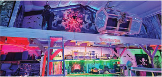 Spooky themed room with colorful lights, Halloween decor, and a large spider.