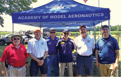 AMA members standing under a blue tent labeled "Academy of Model Aeronautics".