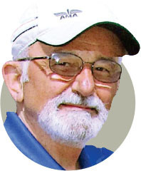 Elderly man with beard and glasses, wearing a white cap with "ANA" logo.