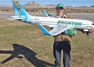 Man holding Frontier model airplane outdoors.