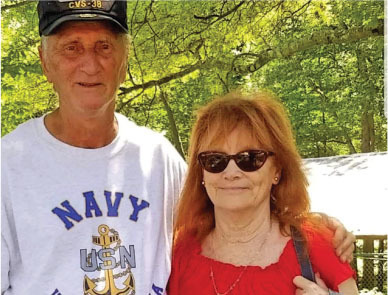 Man in Navy shirt and hat with woman in red shirt and sunglasses, outdoors.