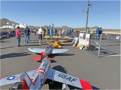 Model airplanes displayed outdoors with people nearby.
