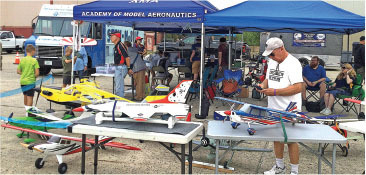 Model aircraft under tents, people observing and interacting.