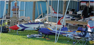 Model planes under a canopy with two people nearby.
