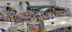 Aircraft exhibition with vintage planes and a large crowd indoors.