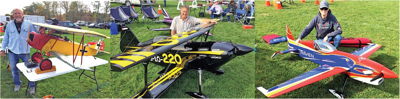 Three men with model airplanes on a grassy field.