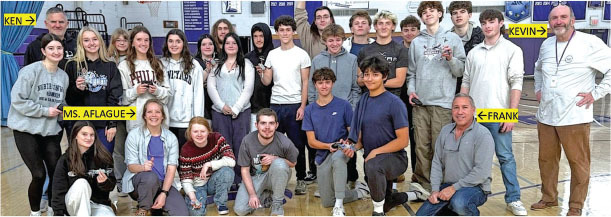 Group of students and teachers smiling in a gymnasium.
