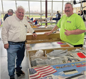 Two men smiling near tables with model airplane kits.