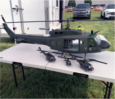 Model military helicopters on a table outdoors.