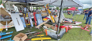 Model airplanes displayed under a tent at an outdoor event.