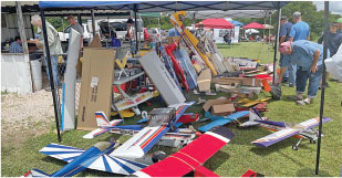 RC model airplanes on display under a canopy at an outdoor event.
