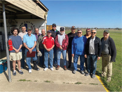Group of men posing outdoors on a sunny day.