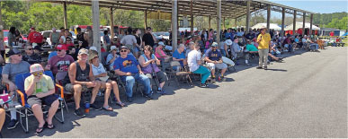 People sitting outdoors under a canopy on a sunny day.