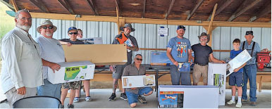 Group of people holding boxed model airplanes under a roofed structure.