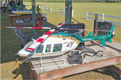 Model helicopter on wooden table outdoors with remote control nearby.