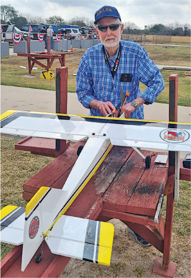 Man with model airplane on outdoor table.