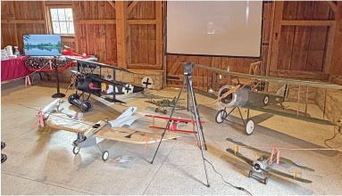 Model airplanes displayed in a wooden barn setting.