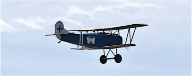 Antique blue biplane flying against a cloudy sky.