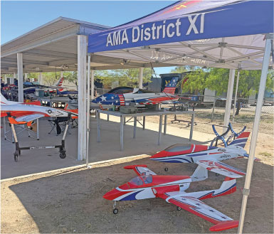 Model airplanes displayed under a tent with "AMA District XI" banner.
